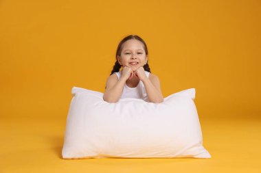 Turuncu arka planda yastığı olan tatlı bir kız.