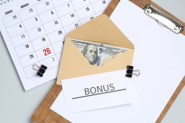 Açık gri zemin üzerinde para, kelime bonusu, pano ve takvim ile zarf düz yatıyordu