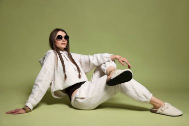 Yeşil arka planda şık giyinmiş güzel bir kadının moda portresi.