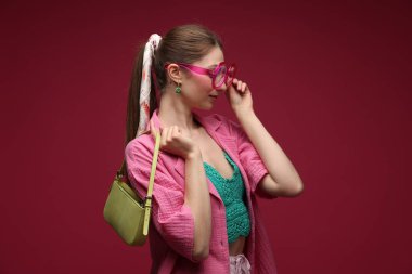 Koyu kırmızı arka planda şık giyinmiş güzel bir kadın portresi.