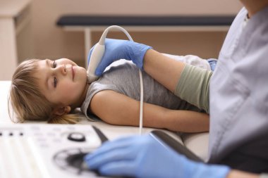 Sonograf, klinikte küçük kızın tiroid bezini ultrason muayenesi yapıyor.