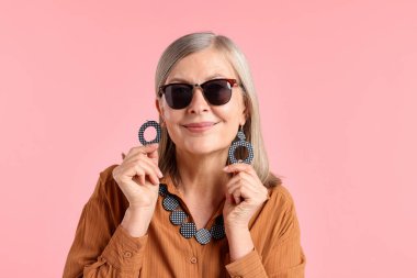 Pembe arka planda şık giyinmiş son sınıf öğrencisi bir kadın.