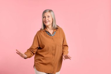 Pembe arka planda şık giyinmiş son sınıf öğrencisi kadın, mesaj için yer var.