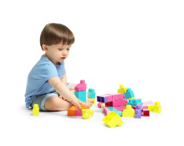 Beyaz arka planda tuğlalarla oynayan sevimli küçük çocuk.