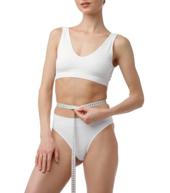 İnce vücutlu ve beyaz arka planda mezurası olan kadın, yakın plan.