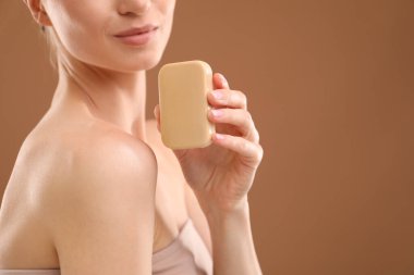 Kahverengi arka planda sabun barı olan bir kadın, yakın plan. Metin için boşluk