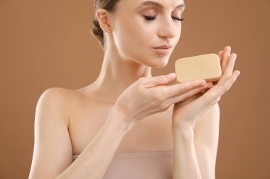 Kahverengi arka planda sabun çubuğu olan güzel kadın, yakın plan.