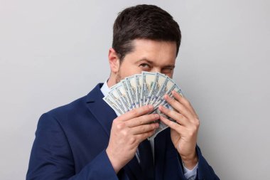 Gri arka planda dolar banknotları olan açgözlü bankacı, yakın plan.