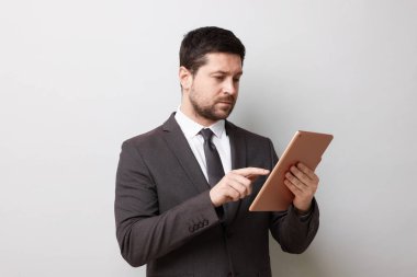 Açık gri arkaplanda tablet kullanan yakışıklı iş adamı