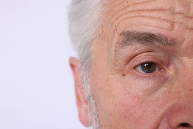 Aydınlık arka planda kendinden emin kıdemli adam, yakın plan