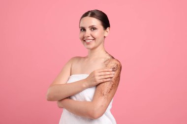 Gülümseyen kadın vücudunu pembe arka plana sürterek koluna sürüyordu.