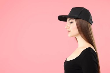 Pembe arka planda şık bir beyzbol şapkası olan güzel bir kadın. Metin için boşluk