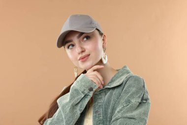 Beyzbol şapkalı güzel bir kadın bej arka planda.