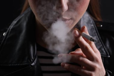 Siyah arka planda sigara içen kadın, yakın plan.