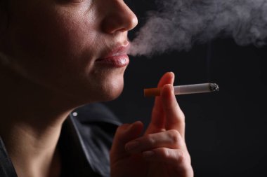 Siyah arka planda sigara içen kadın, yakın plan.
