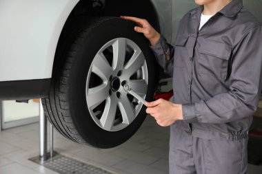 Tamirci araba servisinde lastik değiştiriyor, yakın plan.