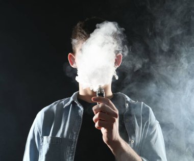 Siyah arkaplanda elektronik sigara içen adam