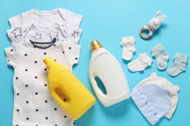 Açık mavi arka planda yumuşatıcı, oyuncak ve bebek kıyafetleri, düz uzanma