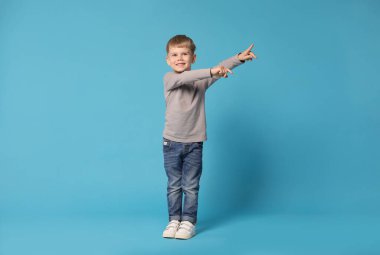 Mutlu küçük çocuk açık mavi arka planda dans ediyor