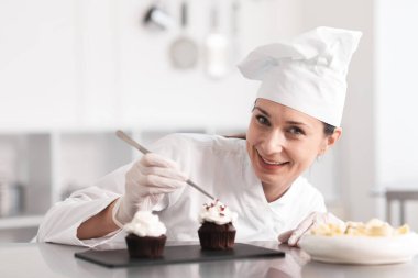 Şekerci, mutfakta çikolata parçalarıyla kek süslüyor.