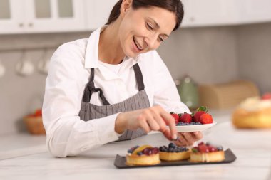Sofrada yaban mersinli tart süsleyen şekerci.