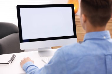 Ofisteki beyaz masada bilgisayarda çalışan bir adam, yakın plan. Tasarım için model