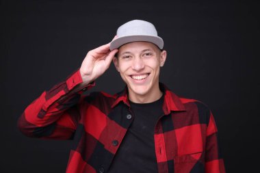 Siyah arka planda şık bir beyzbol şapkası giyen genç adam.