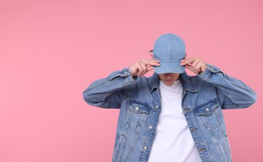 Pembe arka planda şık kot şapkalı genç adam, mesaj için yer var.