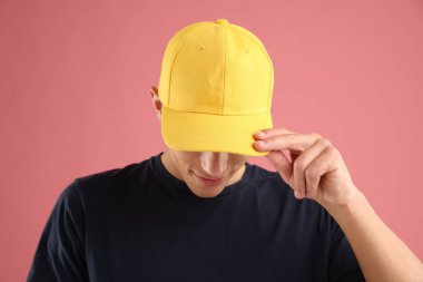 Pembe arka planda şık bir beyzbol şapkası takan genç adam.