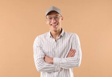 Beyzbol şapkalı genç adam bej arka planda.