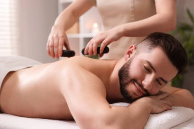 Adam spa salonunda taşlarla masaj yaptırıyor.