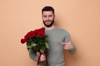 Bej arka planda kırmızı gül buketi olan mutlu adam.