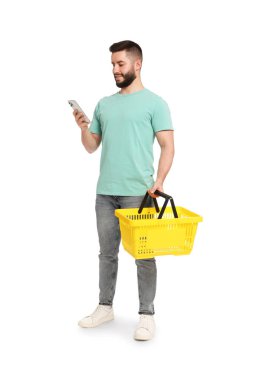 Beyaz arka planda akıllı telefon kullanan boş alışveriş sepetli bir adam.