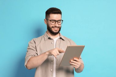 Açık mavi arkaplanda tablet kullanan adam