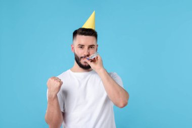 Doğum günün kutlu olsun. Açık mavi arka planda parti şapkası ve üfleyicisi olan yakışıklı adam, metin için yer