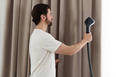 Evde buharlı perdeleri olan bir adam.