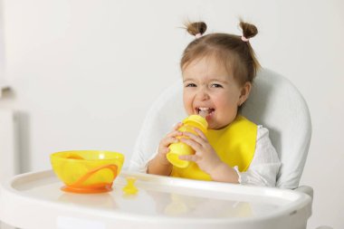 Evdeki yüksek sandalyede biberonla beslenen küçük bebek