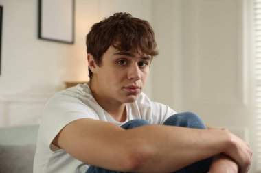Gençlik sorunları. Evde üzgün bir genç çocuk var.