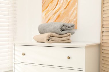 Beyaz çekmeceler üzerinde yün battaniyeler.