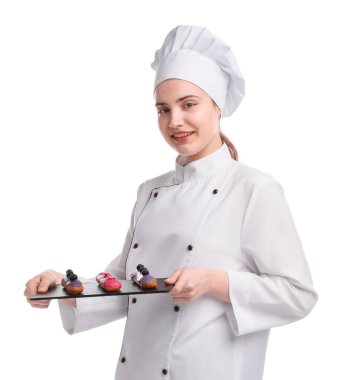 Üniformalı mutlu pastacı beyaz arka planda lezzetli ekinler tutuyor.
