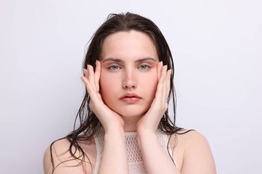 Açık gri arka planda doğal ten rengi olan güzel bir kadının portresi. Yakın plan.