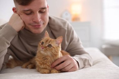 Evdeki kanepede sevimli kızıl kedili adam, seçici odaklı.