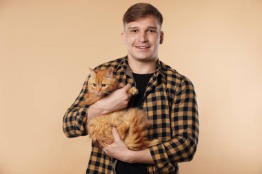 Bej arka planda sevimli kızıl kedisi olan adam.