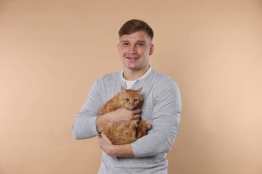 Bej arka planda sevimli kızıl kedisi olan adam.