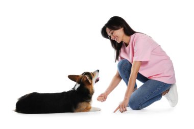 Mutlu kadın köpeğini beyaz arka planda eğitiyor.