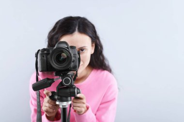 Açık gri arka planda profesyonel video kamerası olan kadın, seçici odaklı. Metin için boşluk