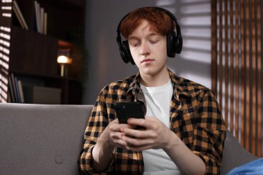 Gençlik sorunları. Evde müzik dinleyen depresif, akıllı telefonlu genç bir çocuk.