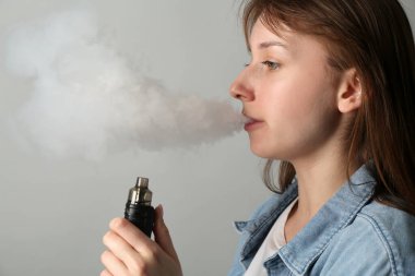 Açık gri arkaplanda elektronik sigara içen kadın