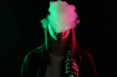 Siyah arka planda neon ışıkları altında elektronik sigara içen kadın