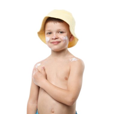 Küçük çocuk beyaz arka planda cildine güneş kremi sürüyor.